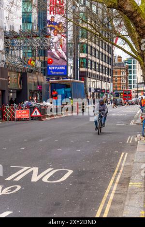 Central London Street mit einem Gebäude im Bau mit Gerüsten und Arbeitern, die Baumaterial von einem LKW und einem Radfahrer entladen Stockfoto