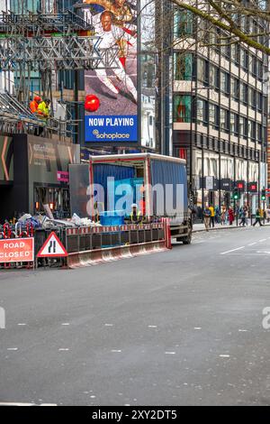 Central London Street mit einem im Bau befindlichen Gebäude mit Gerüsten und Arbeiter in Schutzausrüstung, die Baumaterial aus einem t entladen Stockfoto