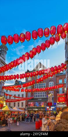 Chinatown Street mit roten chinesischen Laternen, die zwischen den Wänden gebunden sind, und Fußgängern und Touristen, die auf der Straße spazieren gehen und essen, mit vielen Ladenschildern i Stockfoto