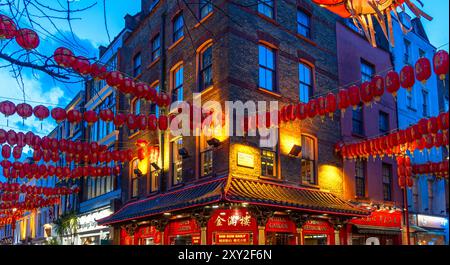 Eine Straßenecke in Soho's Chinatown mit roten chinesischen Laternen, die an den Wänden hängen, unter einem Dämmerungshimmel und einem dekorierten und verzierten typisch chinesischen R Stockfoto