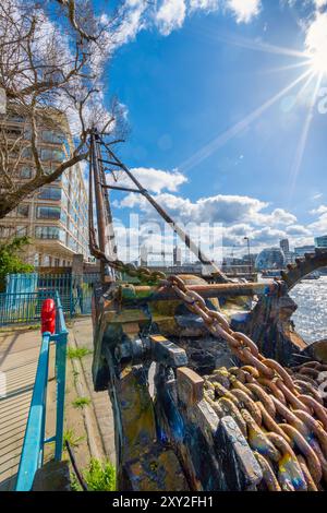 Große rostige Stahlketten mit Spinnweben von den alten Kränen des Hafens der Themse, mit der Turmbrücke im Hintergrund und Blitzen und Strahl Stockfoto