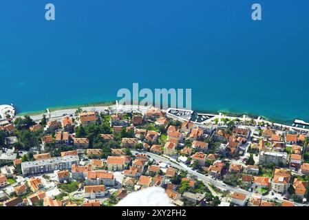 Dobrota aus der Vogelperspektive: Häuser mit Ziegeldächern in der Nähe des Wassers am Stadtrand von Kotor. Immobilien an der Adriaküste, Montenegro Stockfoto