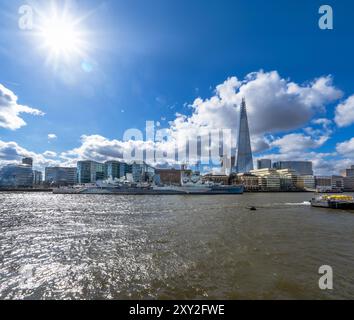 Blick auf die Themse in London mit dem Shard-Wolkenkratzer im Hintergrund und dem Museumsschiff HMS Belfast, das von Linsen und Sonnenstrahlen hinterleuchtet wird Stockfoto