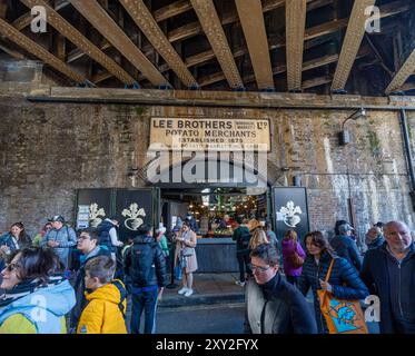 Eingang unter der Eisenbahnbrücke zum modernen Borough Market, mit dem alten Lee Brothers Potato Merchants Schild über dem Eingang zum Marktplatz Stockfoto