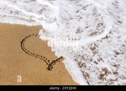 Herzform am Sandstrand Stockfoto