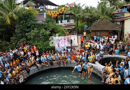 Mumbai, Indien. August 2024. Ein Anhänger springt in die Luft, um während der Feier zum Hindu-fest von Janmashtami in einem Dorf in Alibag einen Topf voller Quark zu brechen. Janmashtami wird von hinduistischen Anhängern als Geburt des Herrn Krishna gefeiert, indem sie hingebungsvolle Lieder singen und einen Tag bis Mitternacht fasten. Am nächsten Tag wird Dahi Handi (Topf gefüllt mit Quark) auf der Straße gefeiert, indem er mit Quark gefüllten Topf zerbrach, als Nachstellung von Lord Krishnas Kindheit, wo er oft Quark und Butter aus dem Topf stehlen würde, der von seiner Mutter in Höhe gehalten wurde. Quelle: SOPA Images Limited/Alamy Live News Stockfoto