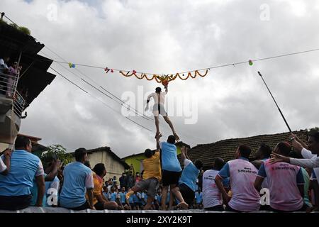 Mumbai, Indien. August 2024. Ein Anhänger springt in die Luft, um während der Feier zum Hindu-fest von Janmashtami in einem Dorf in Alibag einen Topf voller Quark zu brechen. Janmashtami wird von hinduistischen Anhängern als Geburt des Herrn Krishna gefeiert, indem sie hingebungsvolle Lieder singen und einen Tag bis Mitternacht fasten. Am nächsten Tag wird Dahi Handi (Topf gefüllt mit Quark) auf der Straße gefeiert, indem er mit Quark gefüllten Topf zerbrach, als Nachstellung von Lord Krishnas Kindheit, wo er oft Quark und Butter aus dem Topf stehlen würde, der von seiner Mutter in Höhe gehalten wurde. Quelle: SOPA Images Limited/Alamy Live News Stockfoto