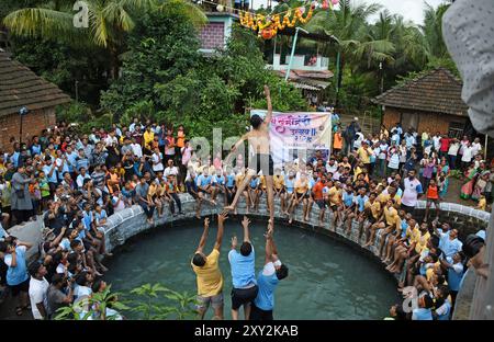 Mumbai, Indien. August 2024. Ein Anhänger springt in die Luft, um während der Feier zum Hindu-fest von Janmashtami in einem Dorf in Alibag einen Topf voller Quark zu brechen. Janmashtami wird von hinduistischen Anhängern als Geburt des Herrn Krishna gefeiert, indem sie hingebungsvolle Lieder singen und einen Tag bis Mitternacht fasten. Am nächsten Tag wird Dahi Handi (Topf gefüllt mit Quark) auf der Straße gefeiert, indem er mit Quark gefüllten Topf zerbrach, als Nachstellung von Lord Krishnas Kindheit, wo er oft Quark und Butter aus dem Topf stehlen würde, der von seiner Mutter in Höhe gehalten wurde. Quelle: SOPA Images Limited/Alamy Live News Stockfoto