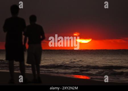 Isle Of Palms, Usa. August 2024. Am 27. August 2024 in Isle of Palms, South Carolina, laufen zwei Männer entlang des Strandes, während die Sonne einen schweren Nebel über dem Atlantischen Ozean durchbricht. Quelle: Richard Ellis/Richard Ellis/Alamy Live News Stockfoto