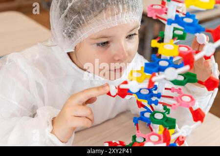 Schulmädchen, das DNA-Modell studiert, im weißen Mantel im Schulklassen. Hochwertige Fotos Stockfoto