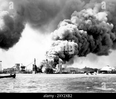 USS Shaw (DD-373) brannte im schwimmenden Trockendock YFD-2 in Pearl Harbor, Hawaii, nachdem sie am 7. Dezember 1941 durch japanische Bombenangriffe in Brand gesetzt worden war. Der brennende Bug der USS Nevada (BB-36) befindet sich auf der rechten Seite. Auf der linken Seite befindet sich ein Motorstart von der USS San Francisco (CA-38). Stockfoto