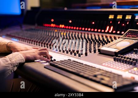 Der Audioingenieur dreht Vorverstärker und Umschalter auf der Schalttafel im Kontrollraum und verwendet eine Mischkonsole zum Bearbeiten und Mastering von Musik. Professioneller Produzent im Musikstudio. Stockfoto