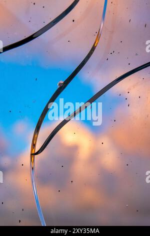 Eine Nahaufnahme von zerbrochenem Glas mit einem leuchtenden Himmel und Wolken im Hintergrund. Stockfoto