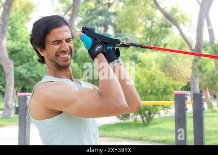 Ein Mann zieht ein Seil, während er ein grünes Hemd trägt. Die Szene ist draußen und er ist ein Park Stockfoto