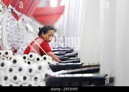 SUQIAN, CHINA - 27. AUGUST 2024 - Ein Arbeiter stellt in einer Werkstatt in Suqian, Jiangs, Kunststoffgewebe für den Export in südostasiatische Länder her Stockfoto