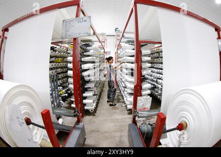 SUQIAN, CHINA - 27. AUGUST 2024 - Ein Arbeiter stellt in einer Werkstatt in Suqian, Jiangs, Kunststoffgewebe für den Export in südostasiatische Länder her Stockfoto