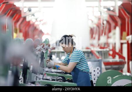 SUQIAN, CHINA - 27. AUGUST 2024 - Ein Arbeiter stellt in einer Werkstatt in Suqian, Jiangs, Kunststoffgewebe für den Export in südostasiatische Länder her Stockfoto