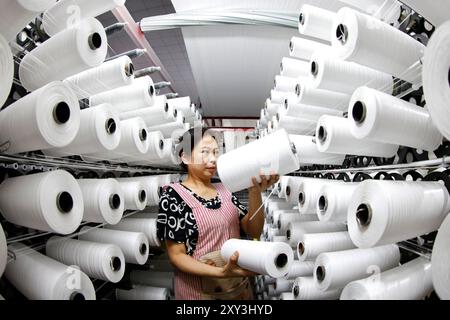 SUQIAN, CHINA - 27. AUGUST 2024 - Ein Arbeiter stellt in einer Werkstatt in Suqian, Jiangs, Kunststoffgewebe für den Export in südostasiatische Länder her Stockfoto