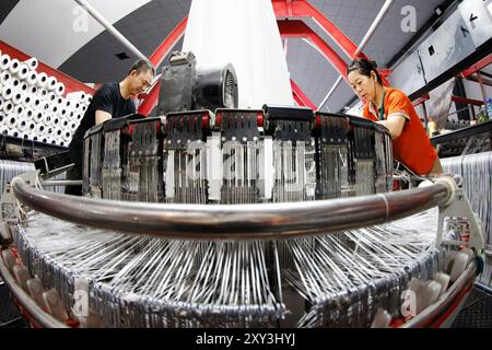 SUQIAN, CHINA - 27. AUGUST 2024 - Ein Arbeiter stellt in einer Werkstatt in Suqian, Jiangs, Kunststoffgewebe für den Export in südostasiatische Länder her Stockfoto