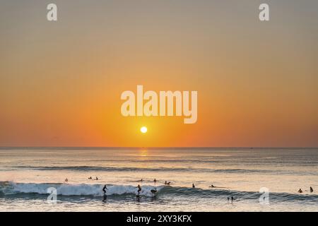 Surfer im Meer, Strand, Urlaub, Sonnenuntergang, Reisen, Strandurlaub, Tourismus, Abendsonne, Abendstimmung, entspannt, entspannend, Sonnenschein, schön, Wetter, Stockfoto