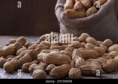Erdnüsse in einem Leinensack auf hölzernen Hintergrund Stockfoto