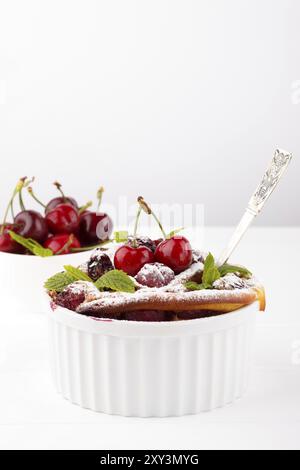 Französische Clafoutis mit Kirsche in Keramik Förmchen auf weißer Holztisch Stockfoto