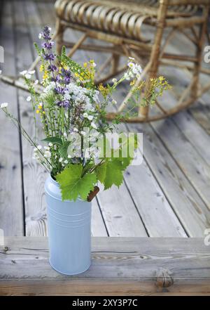 Leuchtend gelben und blauen Eimer mit Blumen auf der Terrasse in der Nähe der Adirondack Schaukelstuhl Stockfoto