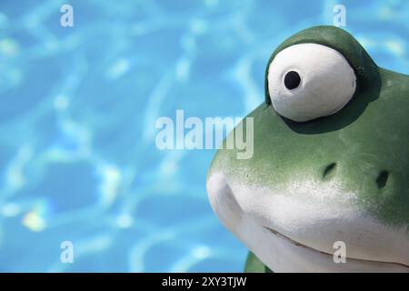 Ein Keramikfrosch vor dem Wasser eines Schwimmbades Stockfoto