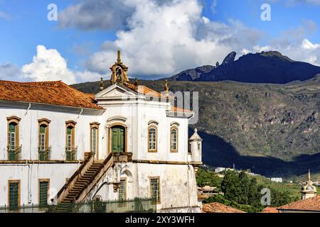 Blick von oben auf die historische Stadt Ouro Preto in Minas Gerais, Brasilien, mit seinen berühmten Kirchen und alten Gebäuden mit Hügel im Hintergrund Stockfoto