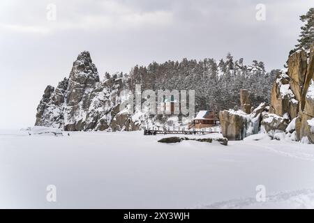 Blick auf Schneeberg und ein Dorf im gefrorenen Baikalsee bei Schneefall Stockfoto