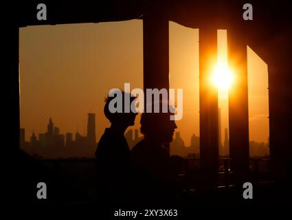 Flushing Meadow, United, Sagte. August 2024. Die Sonne untergeht hinter der Skyline von Manhattan von der Spitze des Arthur Ashe Stadions in der ersten Runde der US Open Tennis Championships 2024 im USTA Billie Jean King National Tennis Center am Dienstag, den 27. August 2024 in New York City. Foto: John Angelillo/UPI Credit: UPI/Alamy Live News Stockfoto