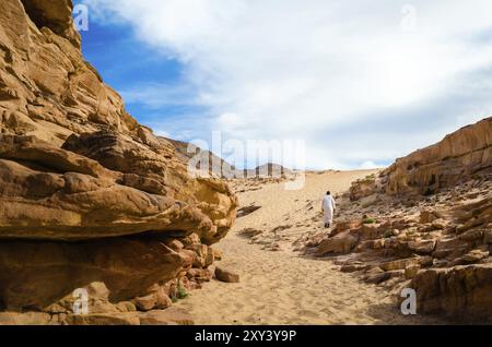 Mann in weißer arabischer Kleidung läuft in einem bunten Canyon in Ägypten Dahab Stockfoto