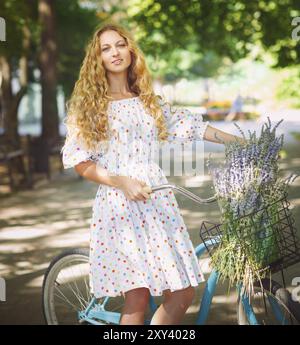 Schöne und glückliche junge Frau mit dem Fahrrad auf der Sommerpark im Hintergrund Stockfoto