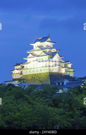 Heller Sonnenuntergang Himmel hinter der alten Himeji-Jo Burg, die abends in Himeji, Japan, über Baumgrenze ragt, nachdem die Renovierungsarbeiten im Jahr 2015 abgeschlossen waren. Vertica Stockfoto