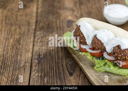 Frisch zubereitetes Falafel Sandwich (Nahaufnahme, selektiver Fokus) auf einem alten Holztisch Stockfoto