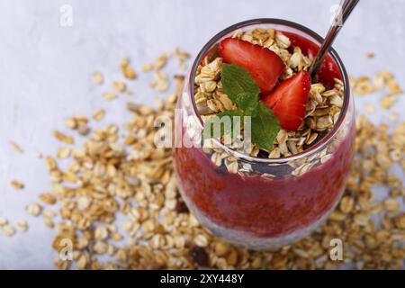 Gesunder Chia, Kokos, Erdbeerpudding mit hausgemachtem Müsli auf weißem Holztisch Stockfoto