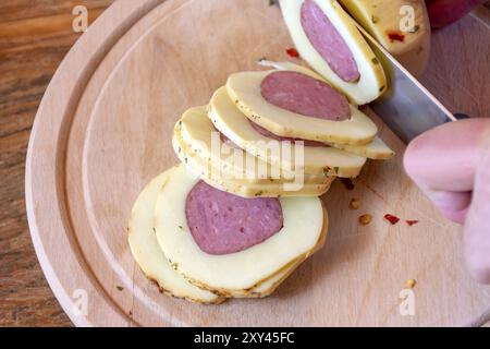 Von Hand in die runde Scheiben mit Salami und Käse mit Paprika pepperoni auf Holzplatte abgedeckt gefüllt Stockfoto