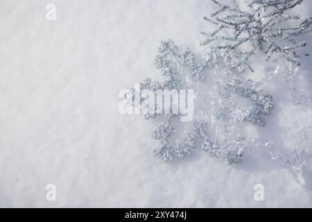 Silberne Weihnachtsdekoration. Wunderschöne Schneeflocke auf echtem Schnee im Freien. Konzept für Winterferien Stockfoto