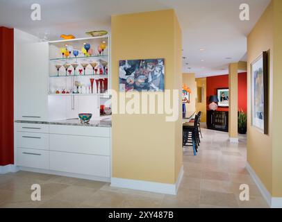 Blick vom Esszimmer zur Küche mit Eckschränken mit farbenfrohen Glaswaren Stockfoto