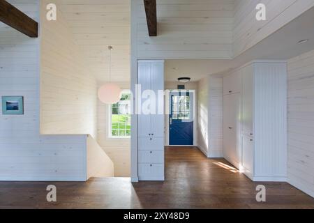 Inneneingangsbereich des Hauses mit blauer Tür und weiß getünchten Kiefernwänden Stockfoto