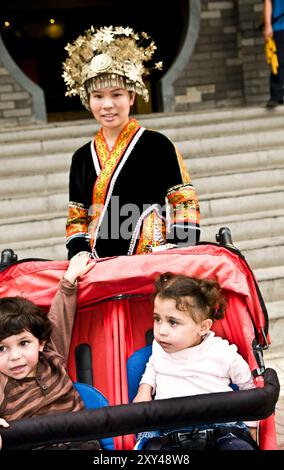 Zwillinge posieren für ein Foto mit einer bunten jungen Chinesin vor einem Restaurant in Nanjing, China. Stockfoto