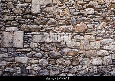 Mittelalterliche Steinmauer Hintergrund oder Textur, die mit verschiedenen Größen der grob geschnittenen Steinen und einige Ziegel zwischen alten Stadt Girona in Spanien Stockfoto