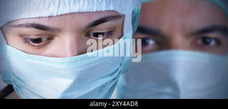 Nahaufnahme zweier Chirurgen während einer Operation. Blauguss und Vignettierung angewendet Stockfoto