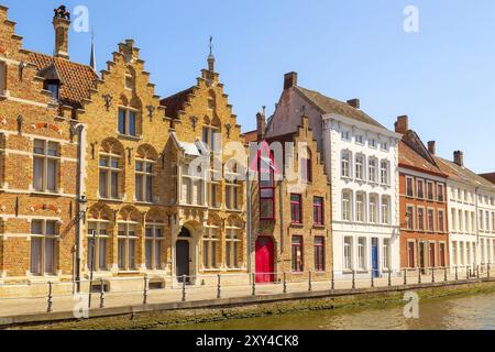 Brügge, Belgien, Panoramablick auf die Straße mit Kanal und farbenfrohen traditionellen Häusern vor blauem Himmel in einem beliebten belgischen Reiseziel Stockfoto