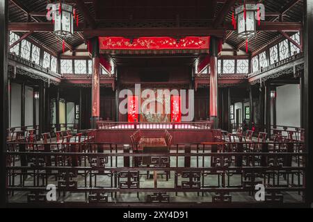 Ein Innenblick auf ein traditionelles chinesisches Theatergebäude mit komplizierten Holzdetails, roten Laternen und einer Bühne. Stockfoto