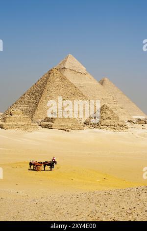 Eine Gruppe nicht erkennbarer ägyptischer Touristen steigt von ihrem Pferdewagen ab, um alle Pyramiden von Gizeh in einer Schlange zu sehen Stockfoto