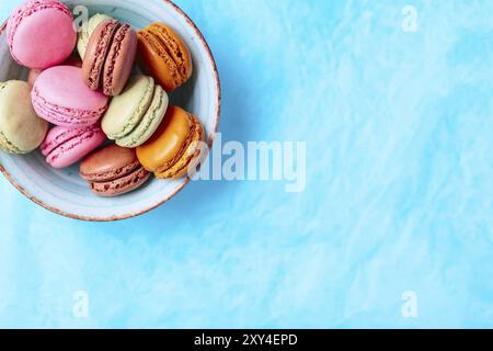 Kuchen Macaron oder makronen Schüssel auf türkis-blauen Hintergrund, Pastellfarben, Ansicht von oben Stockfoto