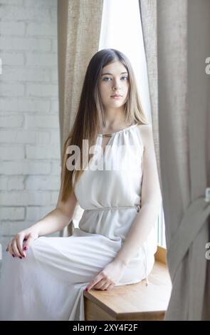 Porträt von ein ziemlich junges Mädchen sitzt auf der Fensterbank Stockfoto