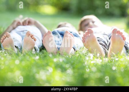 Gruppe glücklicher Kinder, die auf grünem Gras im Frühlingspark liegen Stockfoto