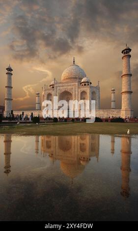 Iconic Taj Mahal und bunten Sonnenuntergang Himmel in eine Pfütze von Wasser auf den Rasen in Abend in Agra, Uttar Pradesh, Indien wider. Vertikale Kopie Raum Stockfoto